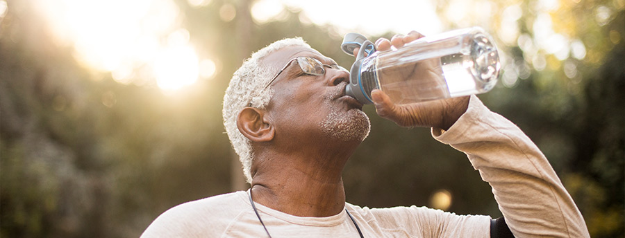 A man drinking out of a water bottle after exercising. 
